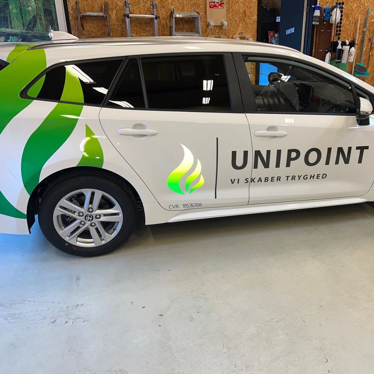 Hvid firmabil med grønne streger folieret på siden 