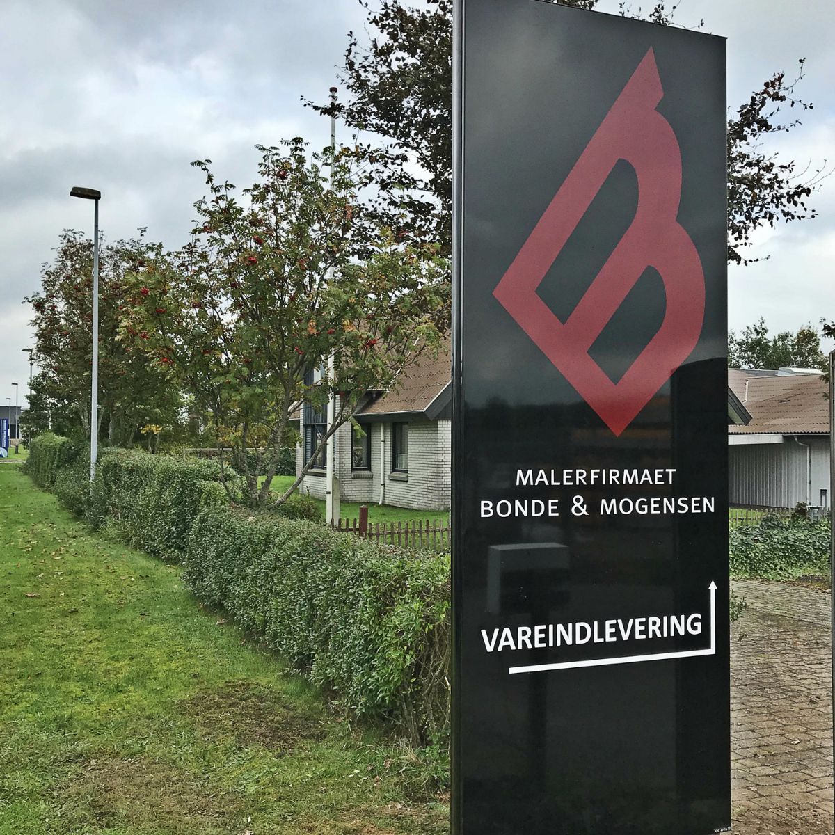 Udendørs pylon- og wayfinding-skilt med logo og teksten ‘Malerfirmaet Bonde & Mogensen – Vareindlevering’, placeret ved indkørsel
