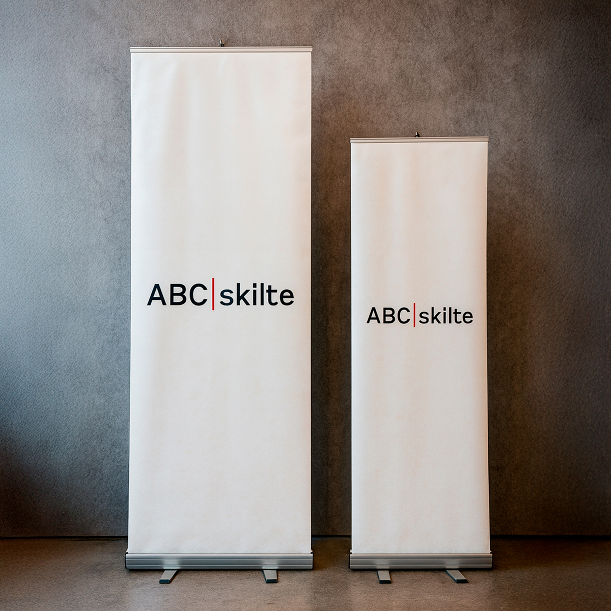 2 forskellige størrelser roll-ups med logo "ABC Skilte" trykt på hvid 