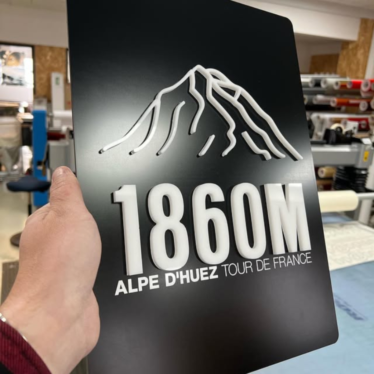 Et sort skilt med formskåret tekst "Alpe D'Huez, Tour de France" 