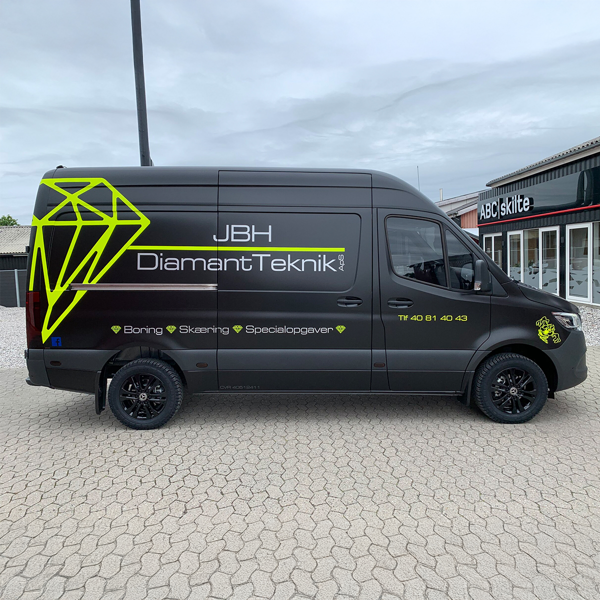Sort arbejdsbil med neon grøn JBH reklame på siden