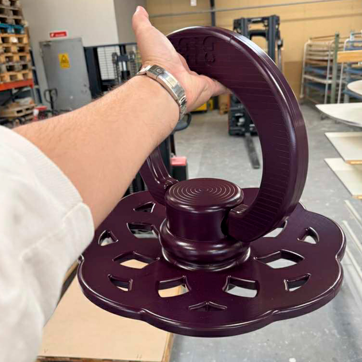 Hånd holder en lilla stor BIBS sut i et værksteds- eller produktionsmiljø