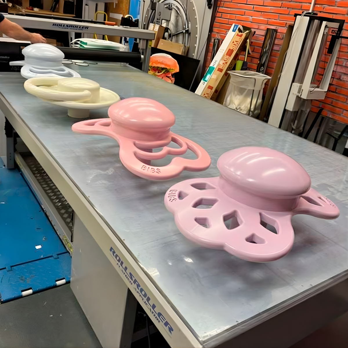 Række af farvede specialfremstillede BIBS sutter, placeret på et arbejdsbord i et produktionsmiljø