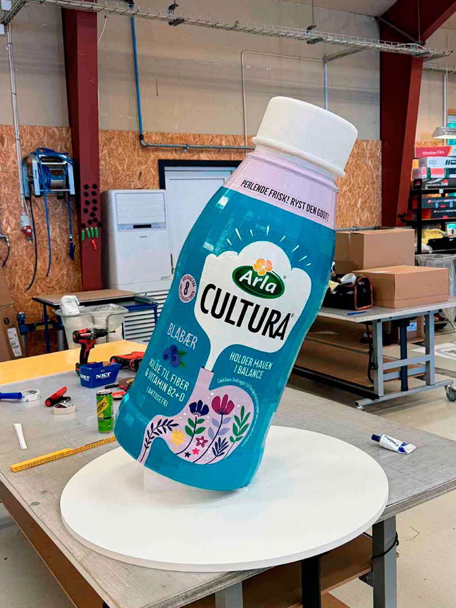 Stor udgave af en Cultura flaske stående skævt på et podie