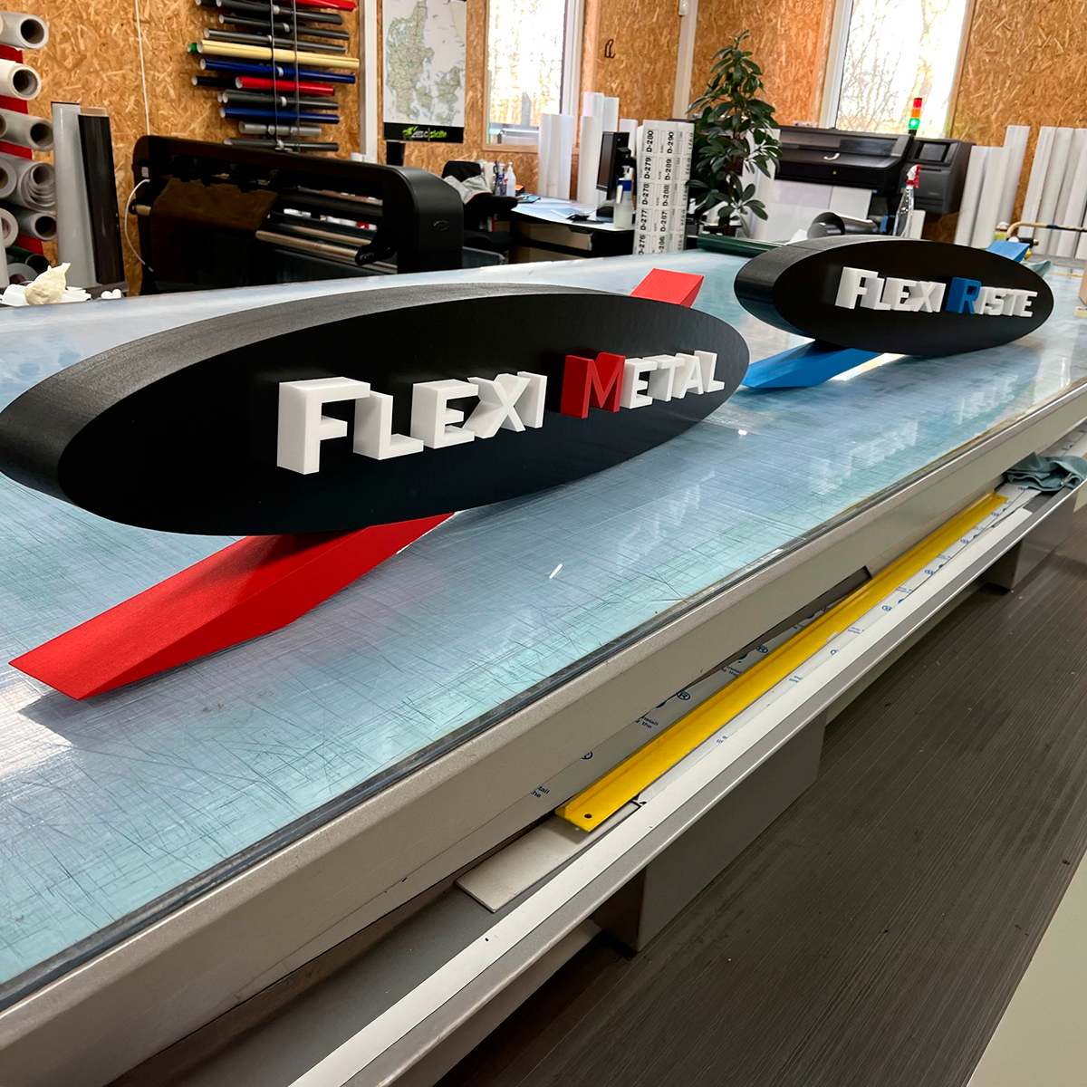 Afrunde skilte på et arbejdsbord med teksten "Flexi Metal" på 