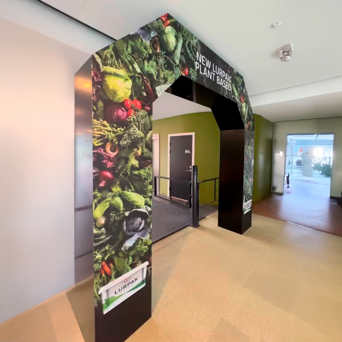 Specialdesignet indgangsportal med grøntsags- og fødevaregrafik, opstillet indendørs i en kontor- eller institutionsgang