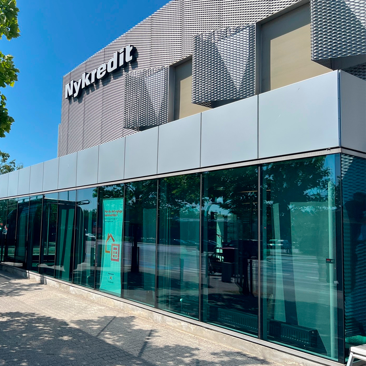 Facade på erhvervsbygning med store glaspartier, facadeskilte og grafiske elementer monteret udvendigt