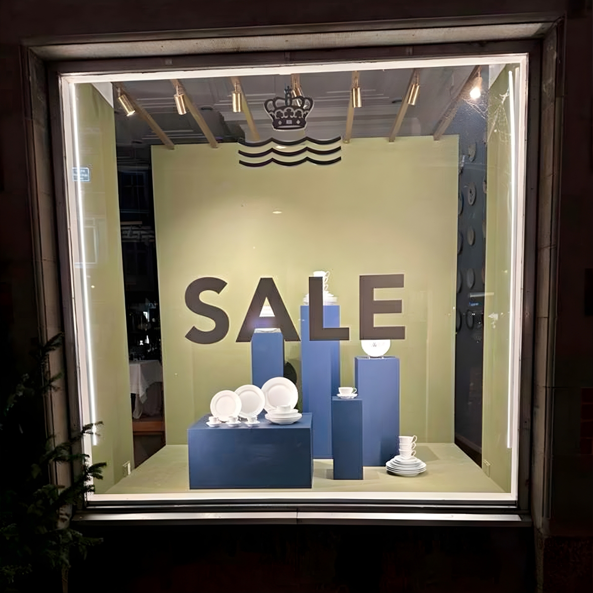 Butiksvindue med udstillingsopstilling og teksten ‘SALE’, brugt som vinduesdekoration til kampagne