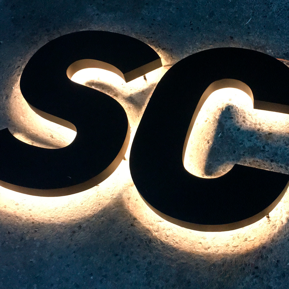 LED bogstaver "S" og "C" med lys bagud på en grå baggrund