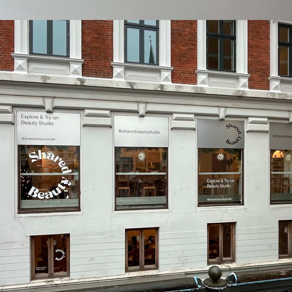 Facade på bygning med butiksvinduer og udvendig vinduesgrafik, der viser butiksskiltning og dekoration