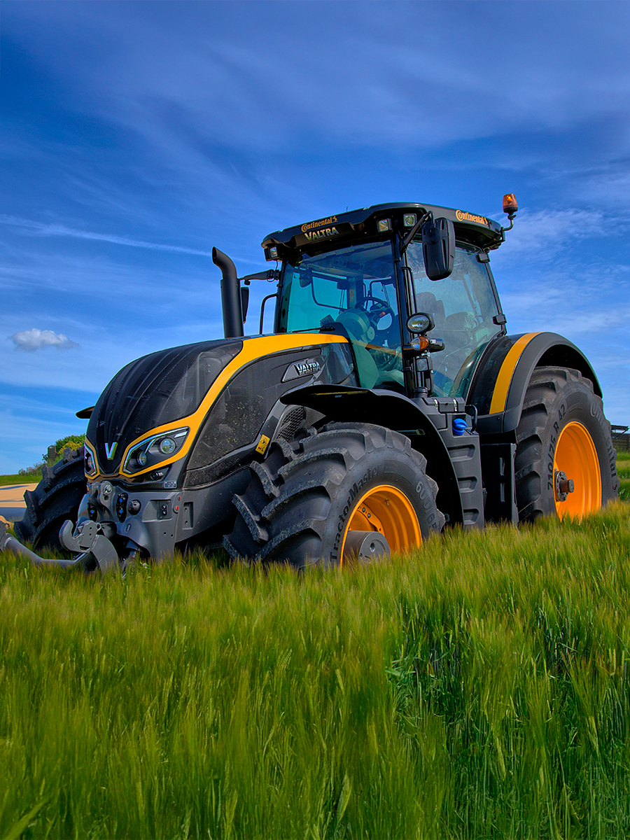 Traktor med sort og orange folie ude på en grøn mark 