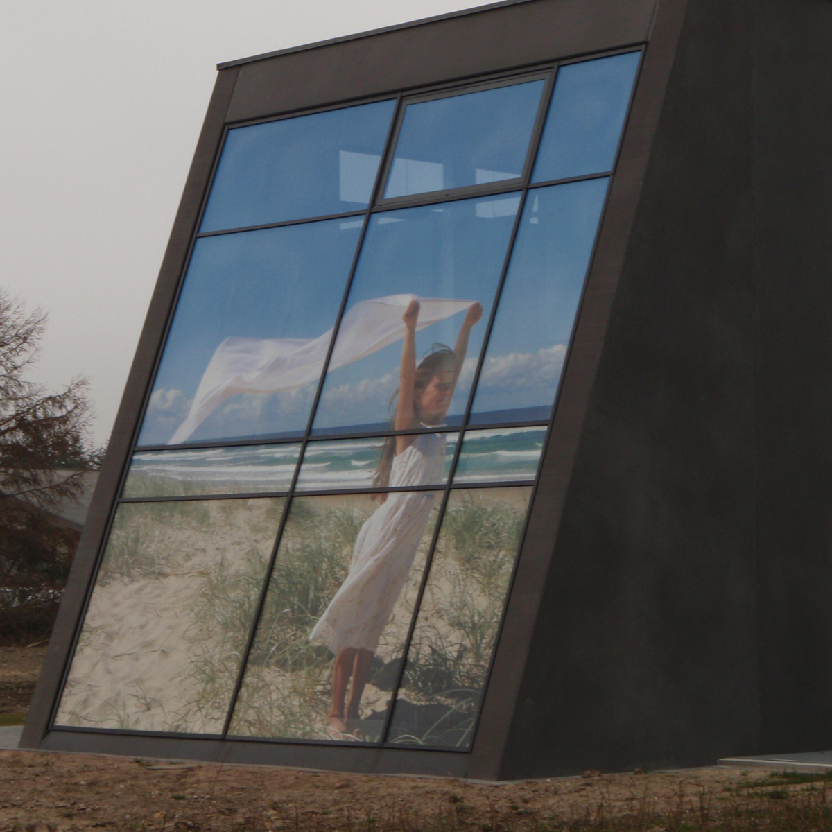 Stor facadevindue med udvendig vinduesgrafik, der viser en person i landskab, monteret på moderne bygning