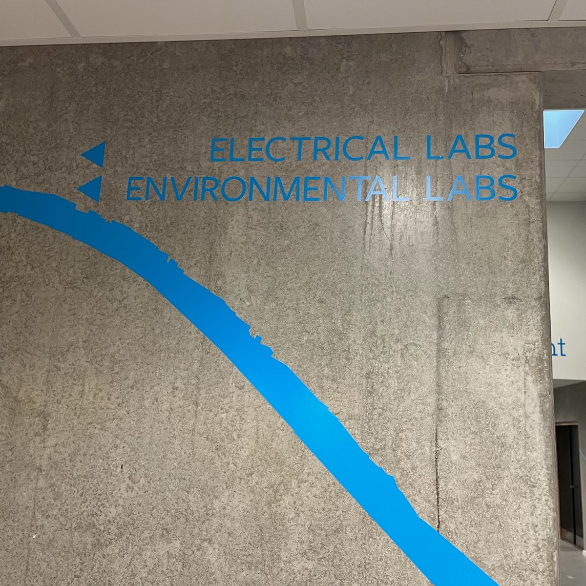 Wayfinding i blå på en betonvæg med lang blå linje og tekst med pile